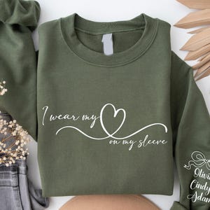 Custom This Mama Wears Her Heart On Her Sleeve Hoodie, Personalized Mom Sweatshirt With Kids Names, Cute Momma Outfit, Mothers Day Gifts