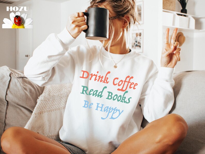 May include: White sweatshirt with the text "Drink Coffee Read Books Be Happy" in colourful lettering.