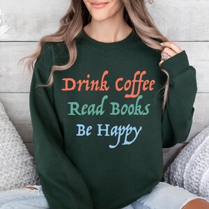 May include: A dark green sweatshirt with the text "Drink coffee Read Books Be Happy" in colourful lettering.