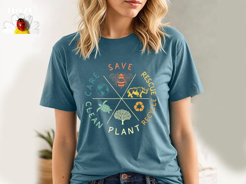Puede incluir: Una camiseta azul turquesa con un dise&ntilde;o gr&aacute;fico circular que presenta una abeja, un rinoceronte, una tortuga, un &aacute;rbol y un globo terr&aacute;queo. El gr&aacute;fico tiene las palabras "Save, Rescue, Recycle, Plant, Clean, Care" alrededor del c&iacute;rculo.