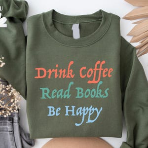 May include: A green sweatshirt with the text "Drink Coffee Read Books Be Happy" in orange, teal, and blue lettering.