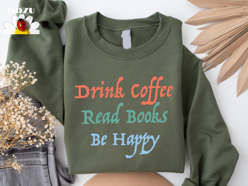 May include: A green sweatshirt with the text "Drink Coffee Read Books Be Happy" in orange, teal, and blue lettering.