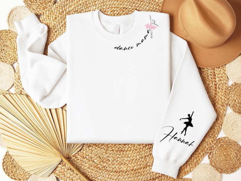 May include: White sweatshirt with the text "dance mama" and a ballerina silhouette on the front. The left sleeve has a ballerina silhouette and the text "Hannah".