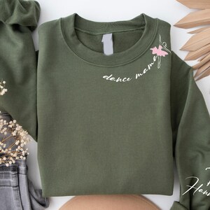 May include: A green sweatshirt with the text "dance mama" and a small ballerina graphic on the front. The right sleeve has the name "Hannah" written on it.