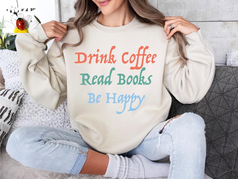 May include: A beige sweatshirt with the text "Drink Coffee Read Books Be Happy" in colourful lettering.