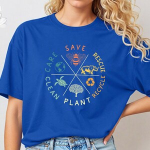 Puede incluir: Una camiseta azul real con un dise&ntilde;o gr&aacute;fico circular que presenta una abeja, una tortuga, un rinoceronte, un &aacute;rbol y la tierra. El gr&aacute;fico est&aacute; rodeado por las palabras "Save", "Rescue", "Recycle", "Plant", "Clean" y "Care".