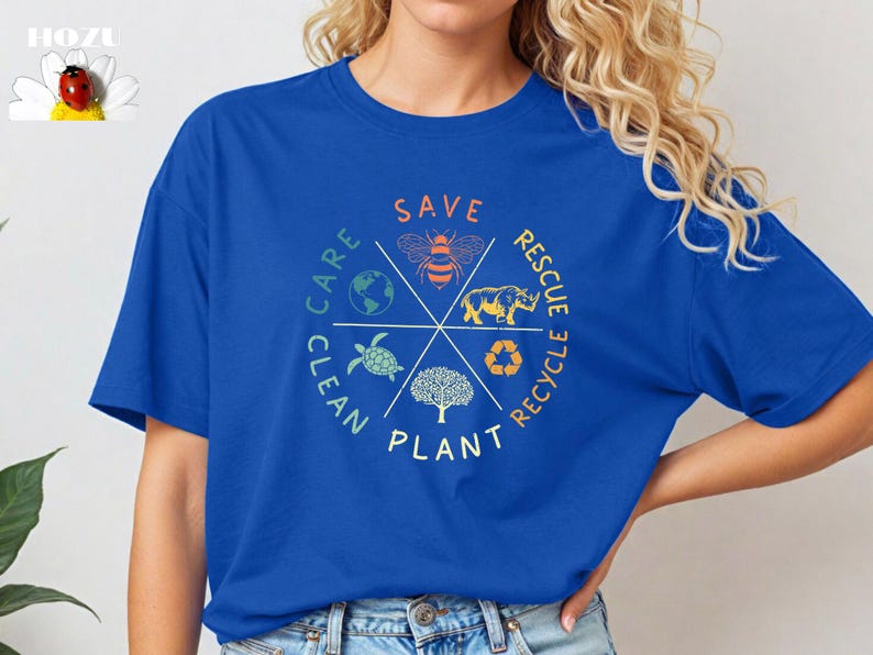 Puede incluir: Una camiseta azul real con un dise&ntilde;o gr&aacute;fico circular que presenta una abeja, una tortuga, un rinoceronte, un &aacute;rbol y la tierra. El gr&aacute;fico est&aacute; rodeado por las palabras "Save", "Rescue", "Recycle", "Plant", "Clean" y "Care".