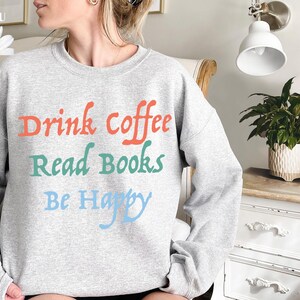 May include: Grey sweatshirt with the text "Drink coffee, Read books, Be Happy" in colourful lettering.