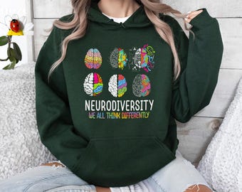 Puede incluir: Una sudadera con capucha verde oscuro con un gráfico de cerebros coloridos y el texto "Neurodiversity We All Think Differently".