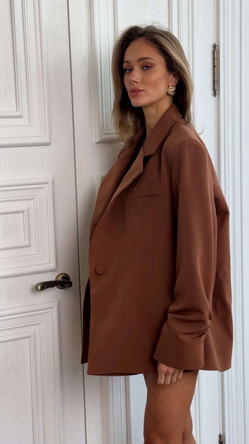 May include: A brown blazer with long sleeves and a single button closure. The blazer has a relaxed fit and a slightly cropped length.