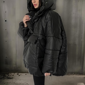 May include: A black puffer jacket with a large hood and a zipper closure. The jacket has a quilted design and a relaxed fit.