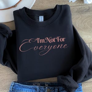 May include: Black sweatshirt with a rose gold graphic that says "I'm Not For Everyone".