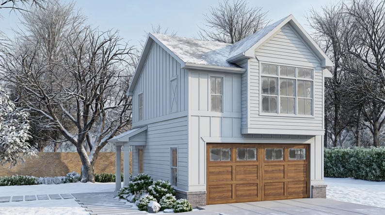 Op de afbeelding: Een huis met twee verdiepingen met een lichtblauwe buitenkant, een bruine garagedeur en een met sneeuw bedekt dak. Het huis heeft meerdere ramen en is omgeven door met sneeuw bedekte bomen en struiken. De lucht is lichtblauw.
