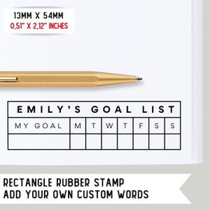 May include: A black and white rubber stamp with the text "EMILY'S GOAL LIST" and a grid with the days of the week labeled "M", "T", "W", "T", "F", "S", and "S". The stamp is 0.51 inches by 2.12 inches.