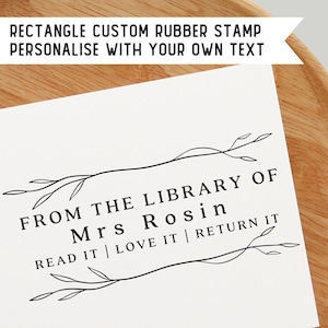 May include: Black and white custom rubber stamp with the text "FROM THE LIBRARY OF Mrs Rosin READ IT | LOVE IT | RETURN IT" surrounded by a simple floral design.