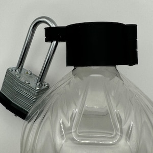 Peut inclure: Une bouteille en plastique transparente avec un bouchon noir sécurisé par un cadenas argenté.