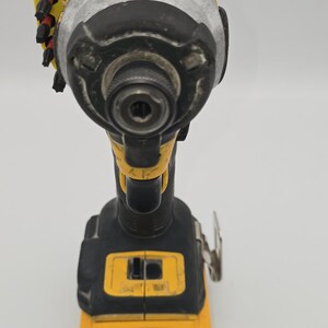 May include: A yellow and black cordless impact driver. The power tool has a silver head and a black handle. The tool has a battery indicator and a trigger. The tool is designed for driving screws and bolts.