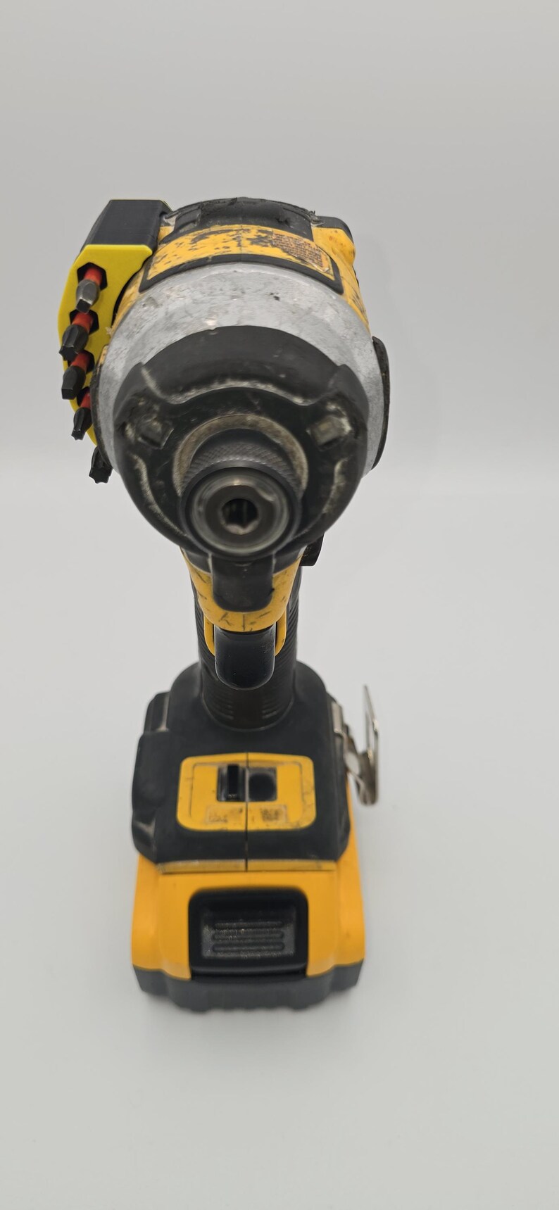 May include: A yellow and black cordless impact driver. The power tool has a silver head and a black handle. The tool has a battery indicator and a trigger. The tool is designed for driving screws and bolts.