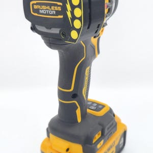 May include: Black and yellow cordless drill with the text "BRUSHLESS MOTOR". The drill has a black handle and a yellow battery pack. The drill is designed for various construction and DIY projects.