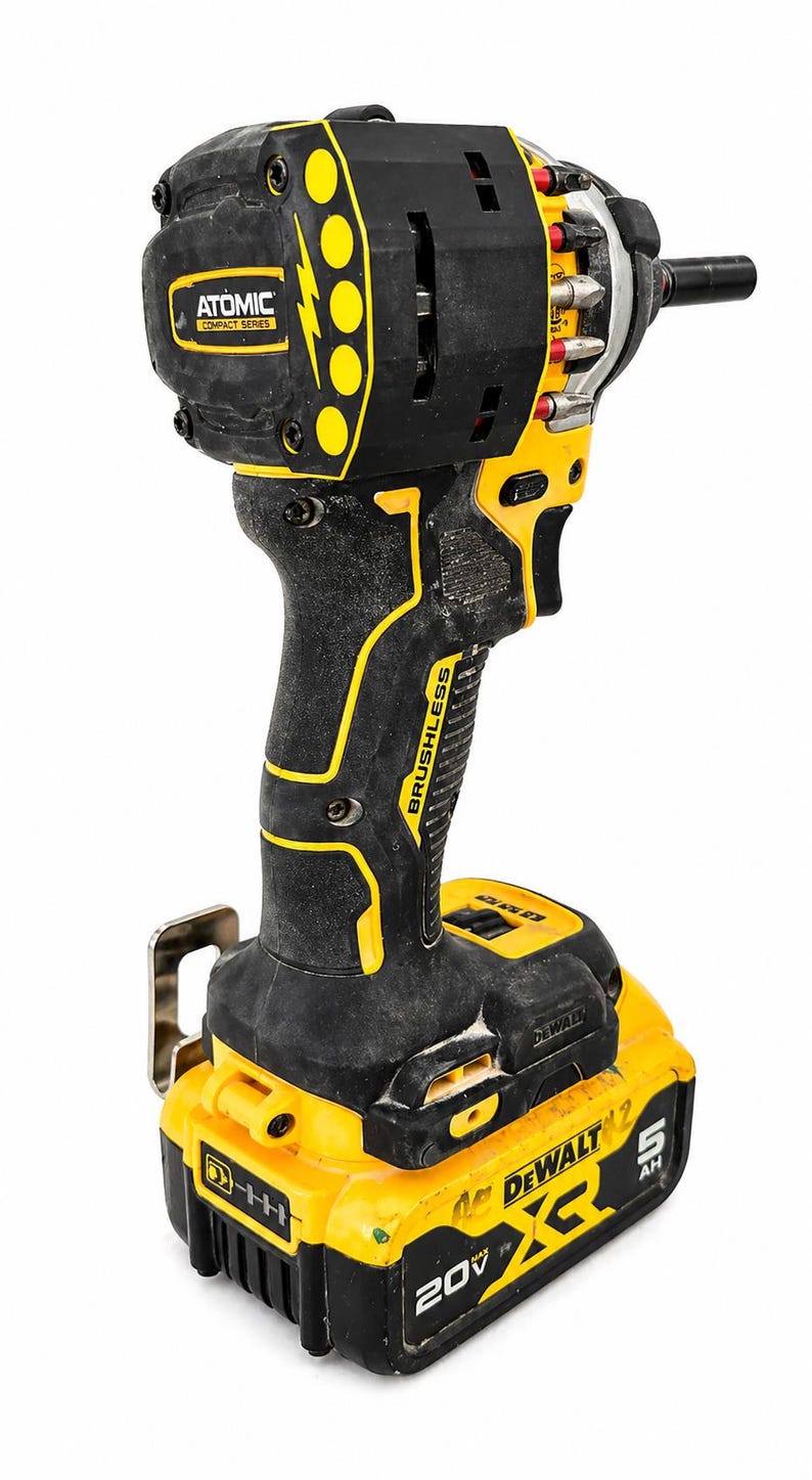 May include: A black and yellow cordless drill with the text "ATOMIC COMPACT SERIES" and "BRUSHLESS". The drill has a black handle with yellow accents and a yellow battery pack. The battery pack reads "DEWALT 20V MAX 5 AH".
