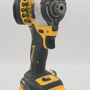 May include: A yellow and black cordless impact driver with a black handle and a yellow battery pack. The tool has the brand name "DEWALT" and "20V" printed on it.