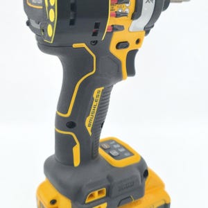 May include: A black and yellow cordless impact driver with a battery pack. The tool has the text "BRUSHLESS MOTOR" and "BRUSHLESS" printed on it. The battery pack has the text "DEWALT XR 20V" and "4 AH" printed on it.