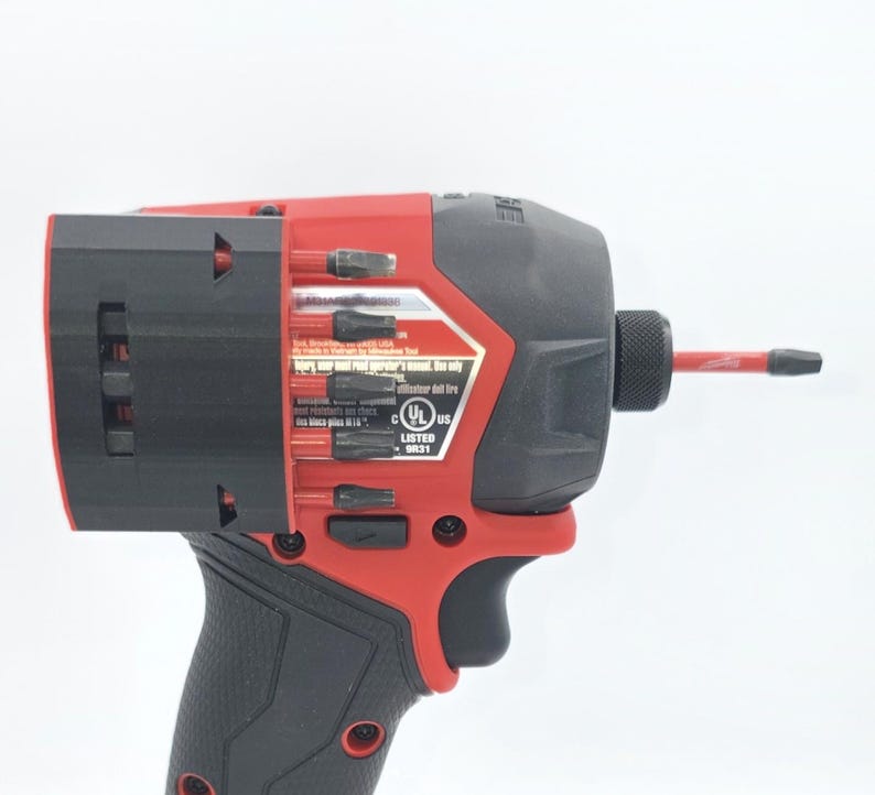 May include: A red and black cordless impact driver with a black handle. The tool has a black head with a red accent and a red bit extending from the front. The tool has a UL Listed sticker.