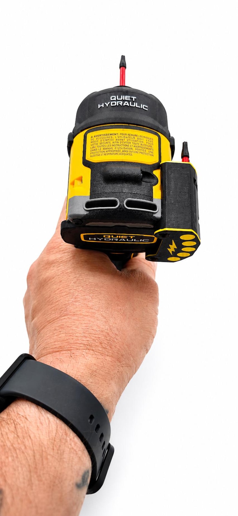May include: A yellow and black hydraulic tool with the text "QUIET HYDRAULIC" is held in a hand. The tool has a black top and a black side component with a lightning bolt symbol. The tool has a red tip.
