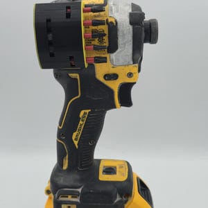 May include: A yellow and black DeWalt impact driver with a black battery pack. The tool has the word "BRUSHLESS" printed on the handle. The battery pack reads "20V" and "4 AH".