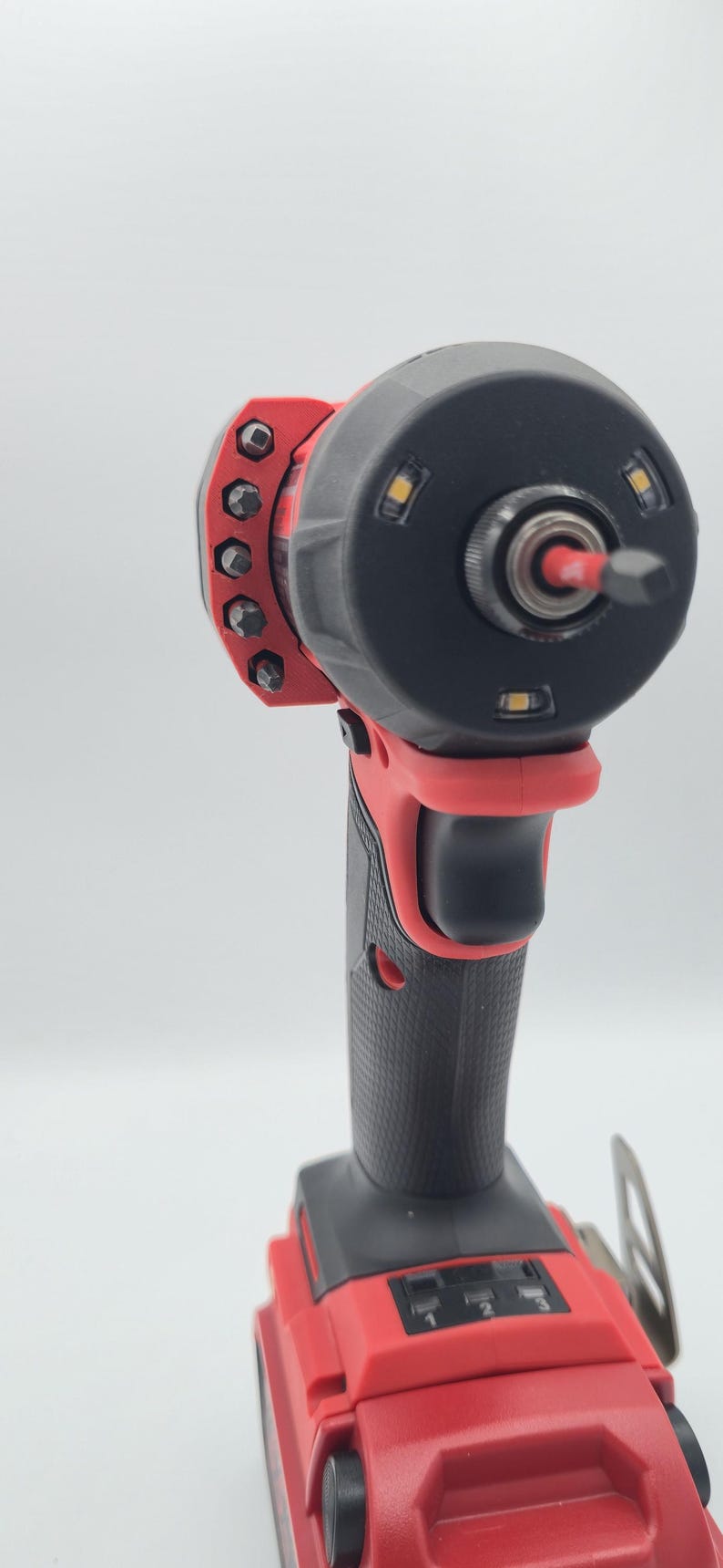 May include: A red and black cordless impact driver with a black head and a variety of bits. The tool has a textured grip and three LED lights around the head.