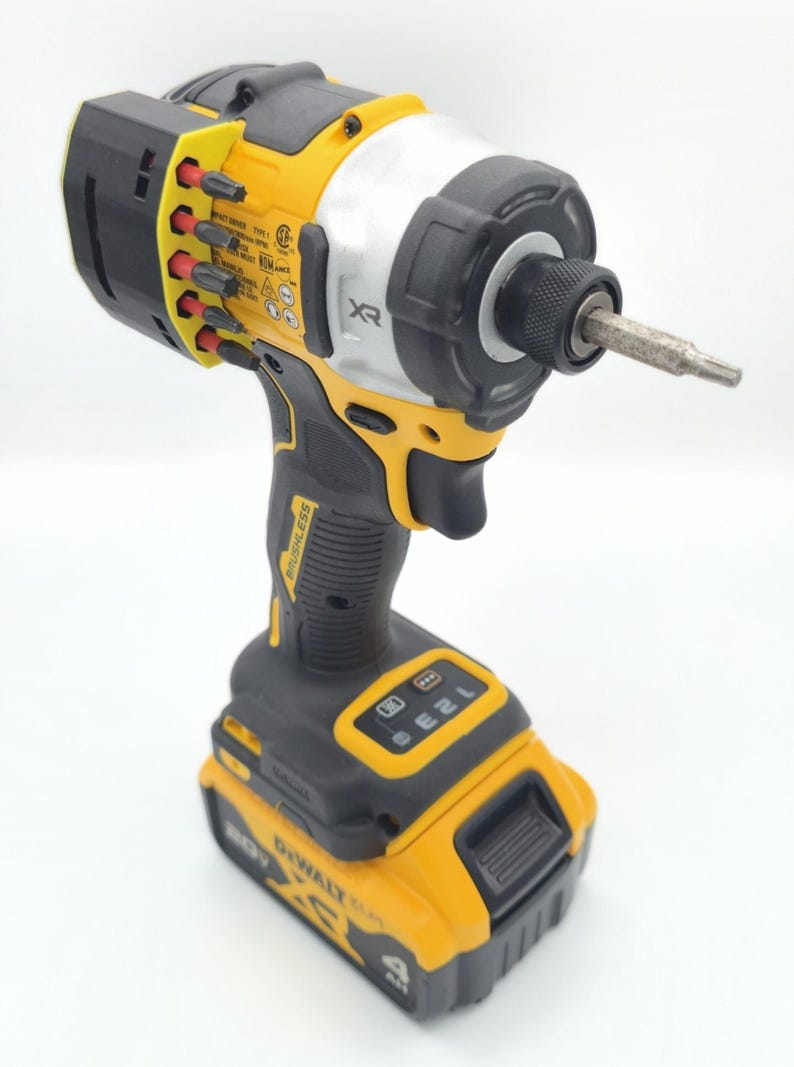 May include: A yellow and black cordless impact driver with a silver head. The tool has a black handle and a battery pack. The brand name "DeWalt" is visible on the battery. A bit is inserted in the front.