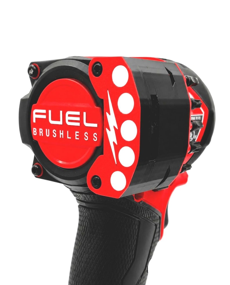 May include: A close-up of a black and red FUEL BRUSHLESS impact wrench. The tool features a red circular center with white text and a red accent with white circles and a lightning bolt design. The handle is black with a textured grip.