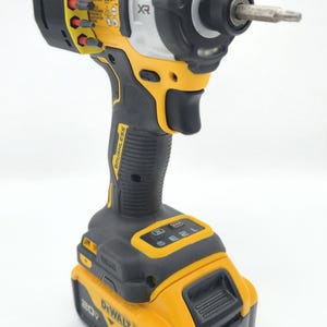 May include: A yellow and black cordless impact driver with a silver bit. The tool has the brand name "DEWALT" and "XR" printed on it. The battery is labeled "20V" and "4 AH".