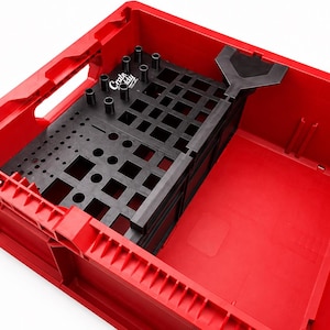 Könnte beinhalten: Eine leuchtend rote Kunststoff-Aufbewahrungsbox mit einem schwarzen Werkzeug-Organizer-Einsatz mit der Aufschrift Crate Caddy. Der Einsatz verfügt über ein Gitter mit verschiedenen runden und quadratischen Aussparungen sowie einen schwarzen Y-Aufsatz.