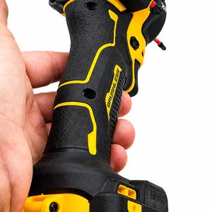 May include: Black and yellow cordless drill with the text "QUIET HYDRAULIC" and "BRUSHLESS". The drill has a black handle with yellow accents and a yellow battery pack with "DEWALT" and "20V" printed on it.