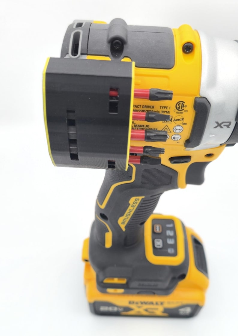 May include: A yellow and black cordless impact driver with a black bit holder attached. The driver has the brand name "DEWALT" and "BRUSHLESS" printed on it. The bit holder contains several black and red bits.