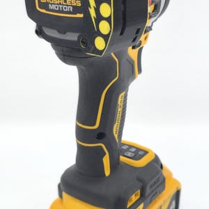 May include: Black and yellow cordless drill with a brushless motor. The drill has a black handle and body with yellow accents and a yellow battery pack. The text "BRUSHLESS MOTOR" is visible on the drill.