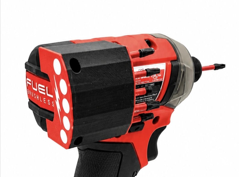 Puede incluir: Un atornillador de impacto sin escobillas FUEL rojo y negro. La herramienta tiene un mango negro, un cuerpo rojo y un extremo frontal negro. El extremo frontal tiene un panel rojo con puntos blancos y la palabra "FUEL". Una cubierta de pl&aacute;stico transparente est&aacute; en la parte superior.