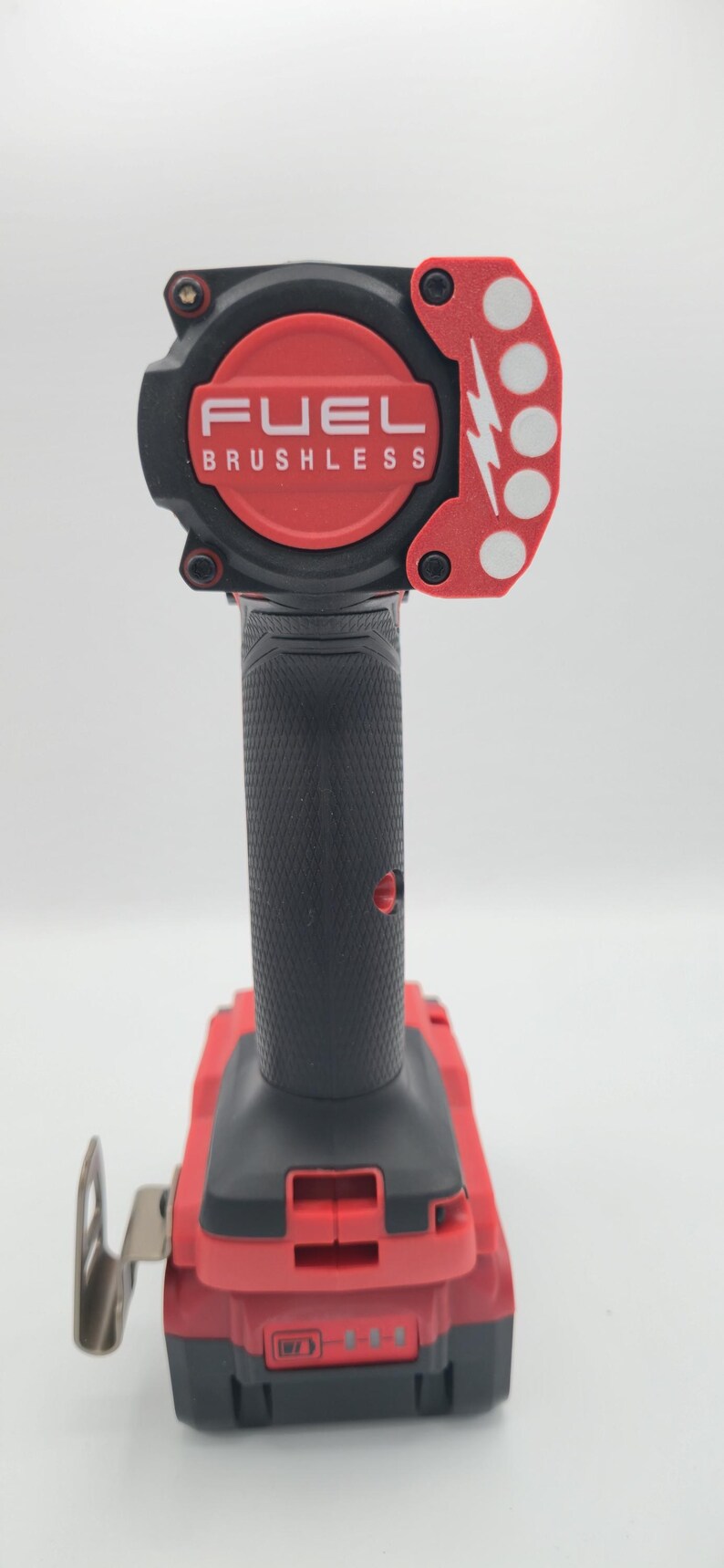 May include: Red and black FUEL brushless impact wrench. The tool has a black handle with a textured grip and a red base. The head of the tool is red with the word FUEL and the word BRUSHLESS in white.