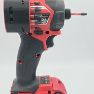 May include: A red and black cordless impact driver with a black handle and a red battery pack. The battery pack is labeled "LITHIUM-ION 6.5AH 18V". The tool has a black chuck and a red bit.