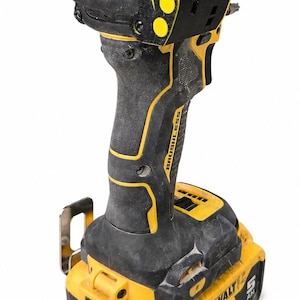 May include: A black and yellow cordless impact driver with the text "ATOMIC COMPACT SERIES" and "BRUSHLESS". The battery pack reads "DEWALT" and "20V".