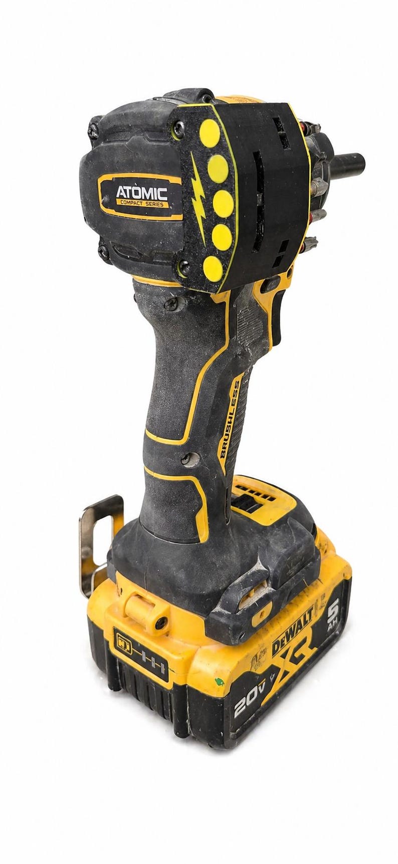 May include: A black and yellow cordless impact driver with the text "ATOMIC COMPACT SERIES" and "BRUSHLESS". The battery pack reads "DEWALT" and "20V".