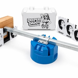 May include: A collection of tools for electrical work, including a white plastic container with the text "Deeper Daddy" and a graphic of a woman, a blue base, and a metal bar. Also included are black and white graphic cards.