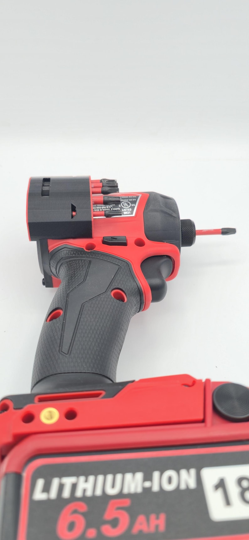 May include: A red and black cordless impact driver with a black grip. The tool has a black head and a red battery pack. The battery pack reads "LITHIUM-ION 6.5AH 18V".