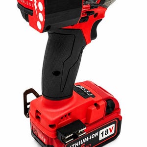 Puede incluir: Un atornillador de impacto inal&aacute;mbrico rojo y negro con un agarre negro y una bater&iacute;a. La herramienta tiene el texto "FUEL BRUSHLESS" y "LITHIUM-ION 18V 6.5Ah" impreso.