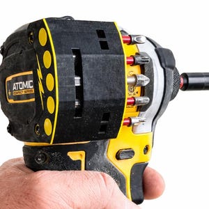 May include: A black and yellow Atomic Compact Series impact driver with various bits attached. The tool has a black handle and a yellow accent. The text "ATOMIC COMPACT SERIES" is visible on the side of the tool.