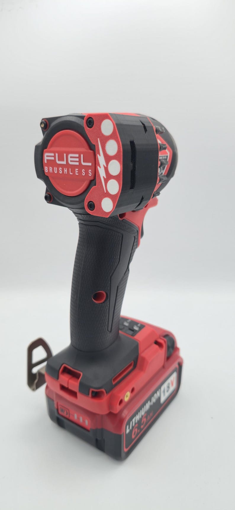 May include: A red and black cordless impact driver with the text "FUEL BRUSHLESS" on the head. The battery pack reads "LITHIUM-ION 18V 6.0 Ah".