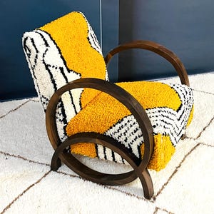May include: A yellow and white patterned armchair with a dark wood frame. The chair has a unique design with curved arms and a rounded back.