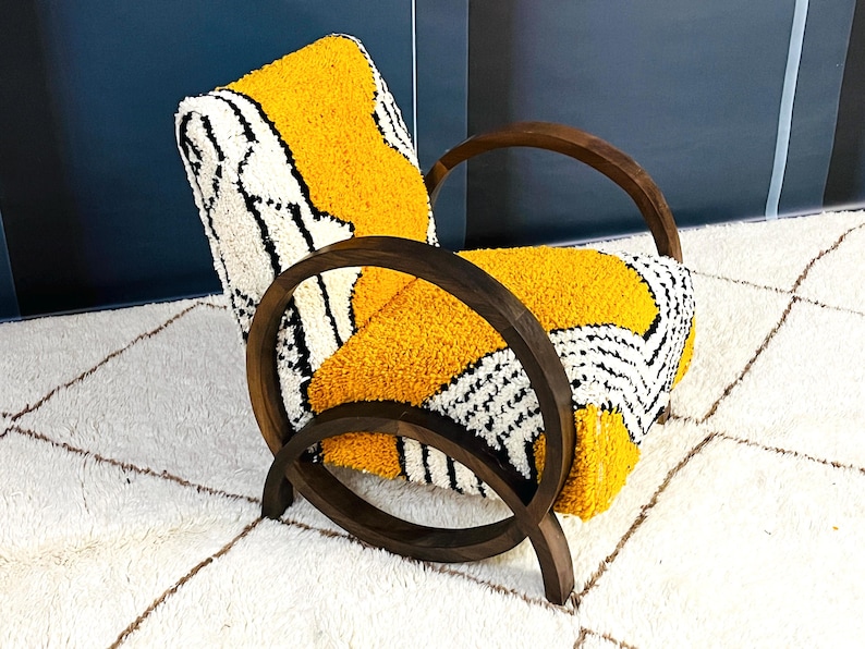 May include: A yellow and white patterned armchair with a dark wood frame. The chair has a unique design with curved arms and a rounded back.