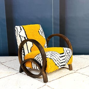 May include: A yellow and white patterned armchair with a dark wood frame. The chair has a unique curved design and is sitting on a white rug.